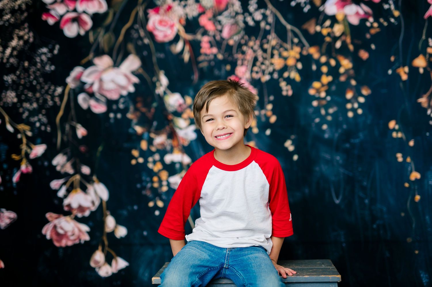 in studio photography with floral backdrop; indoor photography set up; young boy with baseball shirt; tulsa oklahoma