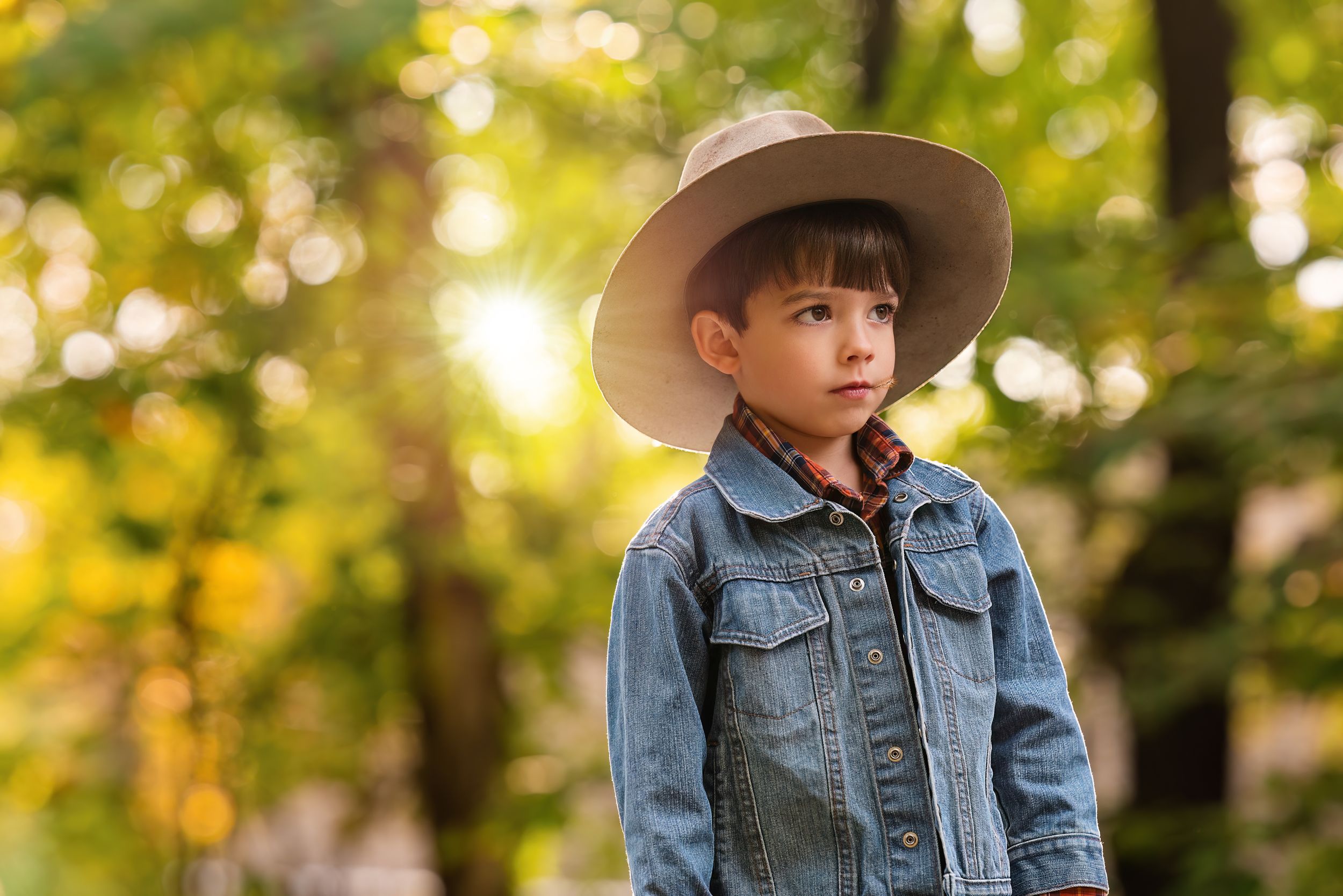 boy in hat looks off camera in outdoor golden light