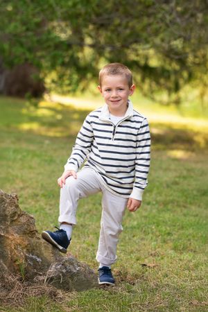 young boy poses for camera in outdoor photo