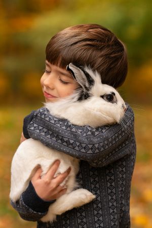boy snuggles with pet rabbit