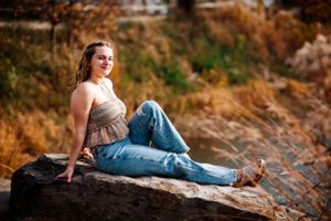 Casual portrait on rocky terrain wearing tank top and jeans during golden hour.