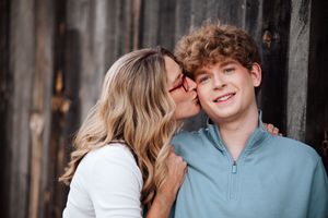 A couple shares an intimate moment in front of a rustic wooden wall while wearing casual attire in Perrysburg, Ohio.