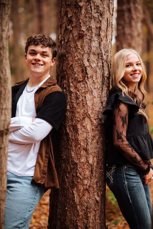 Playful outdoor portrait series showing couple peeking around tree trunks in autumn forest setting.