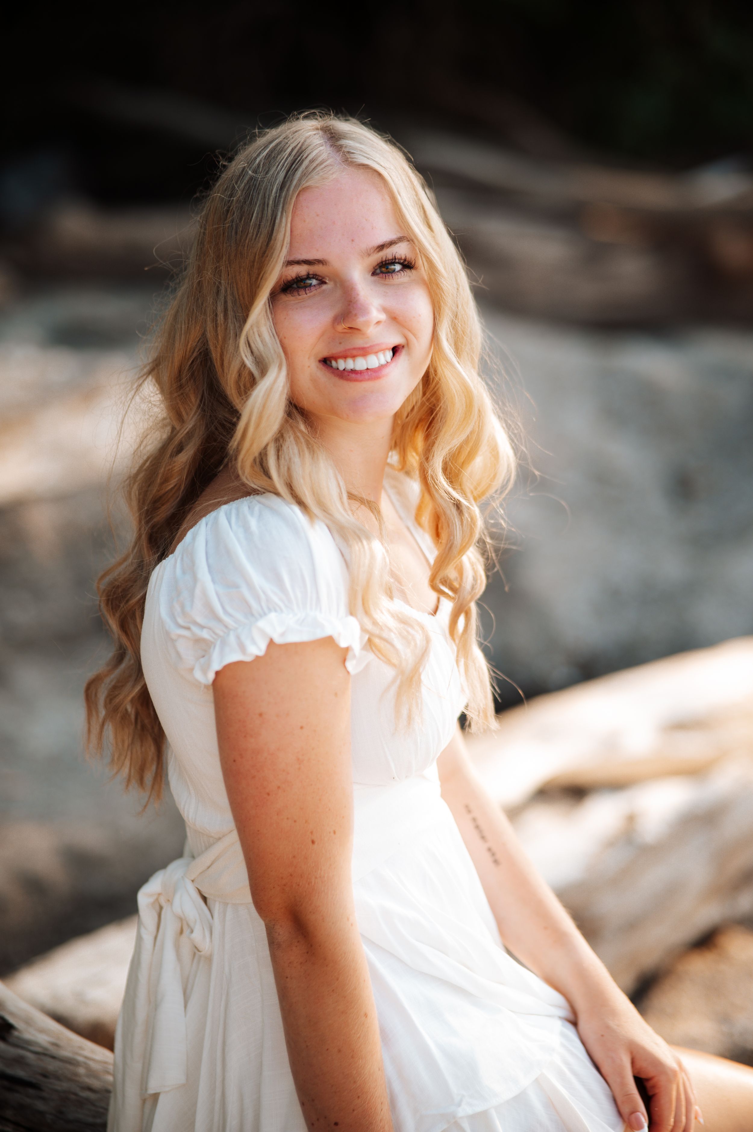 Young woman in white dress poses outdoors in natural sunlight for a series of portrait photographs.
