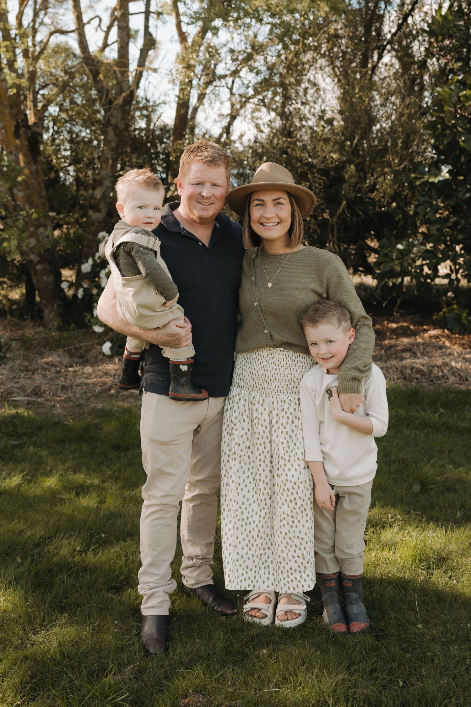 A series of candid outdoor family portraits showing playful moments in a grassy area with trees in the background.