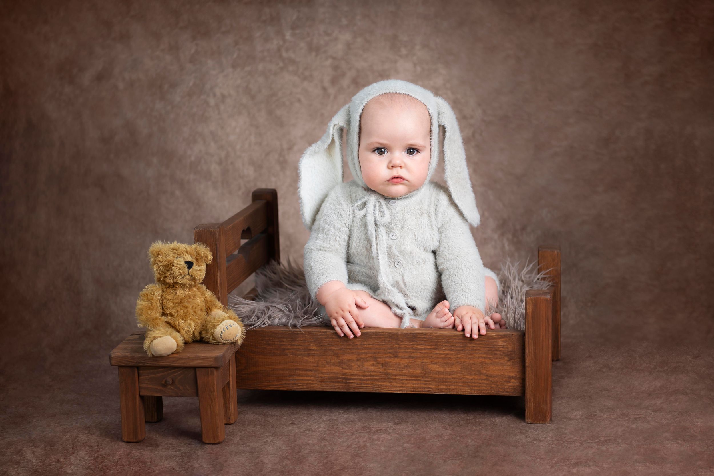 little sitter studio photo based in ashford kent chils dressed as a bunny sitting on a wooden bed