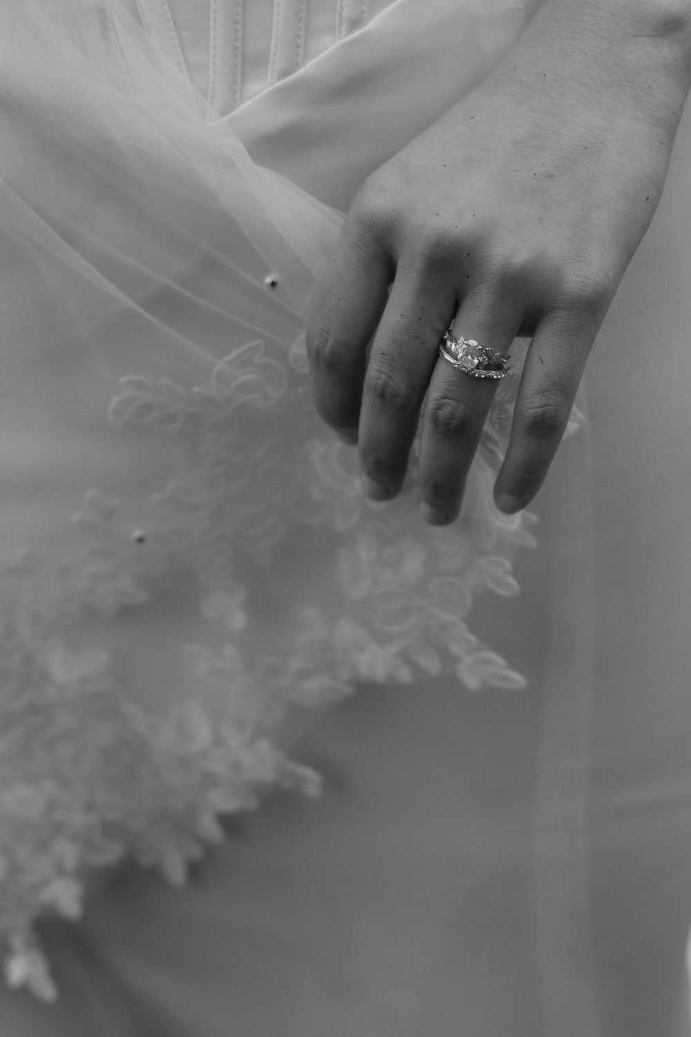 Close-up sequence showing a diamond engagement ring sparkling on a hand against a soft white tulle background.