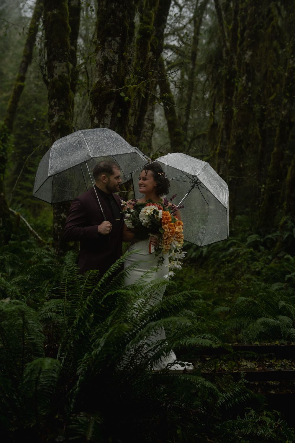 A romantic rainy day photoshoot in a misty forest with clear umbrellas and autumn colors.