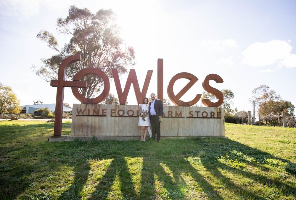 Large red 'TOWIES' sign stands atop a grassy hill against a bright blue sky during sunset.