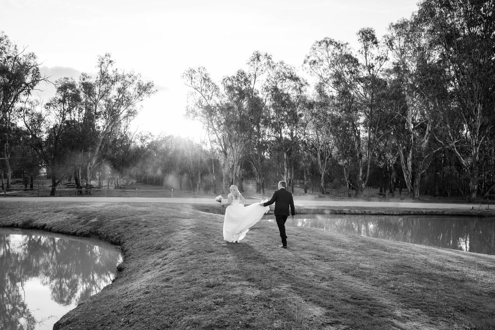 A black and white panoramic sequence shows a person walking along a rural dirt road surrounded by trees at dusk.
