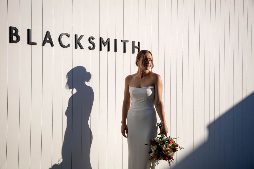 A white wall displays the word 'BLACKSMITH' in black letters with shadows cast from figures standing nearby.