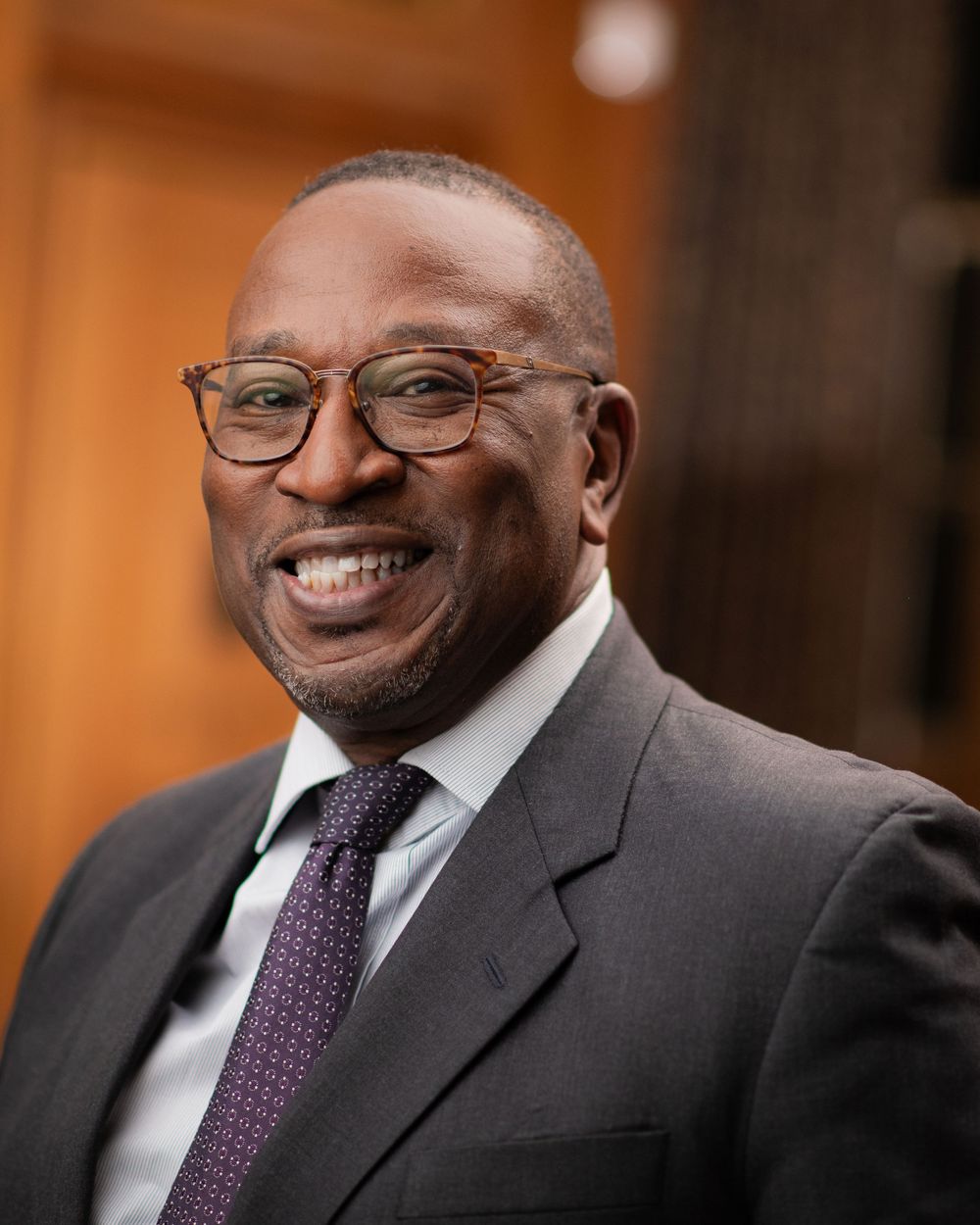 Professional portrait series showing a person in a dark suit and purple tie smiling warmly against a blurred background.