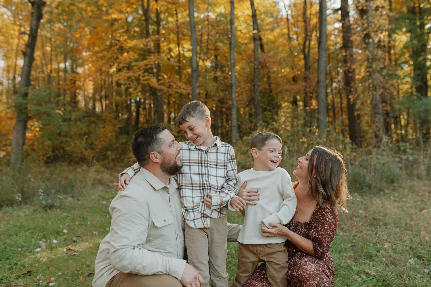 A family shares a joyful moment together in an autumn forest setting.
