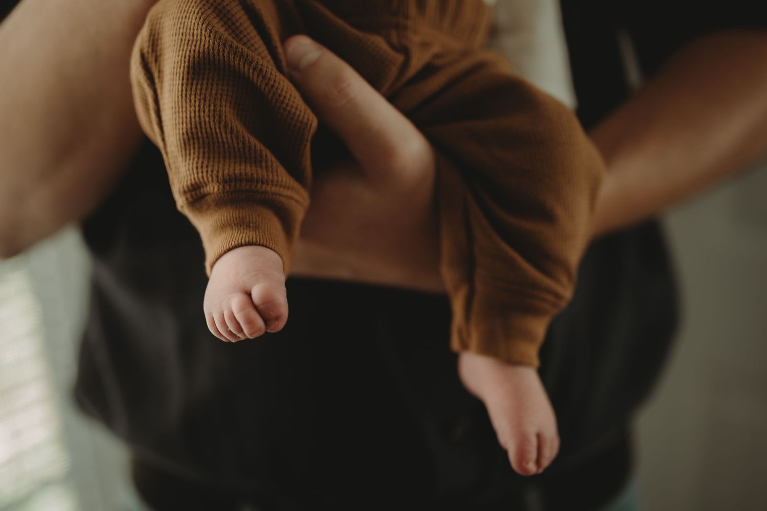 Intimate newborn photography with soft white wrapping and delicate lighting.