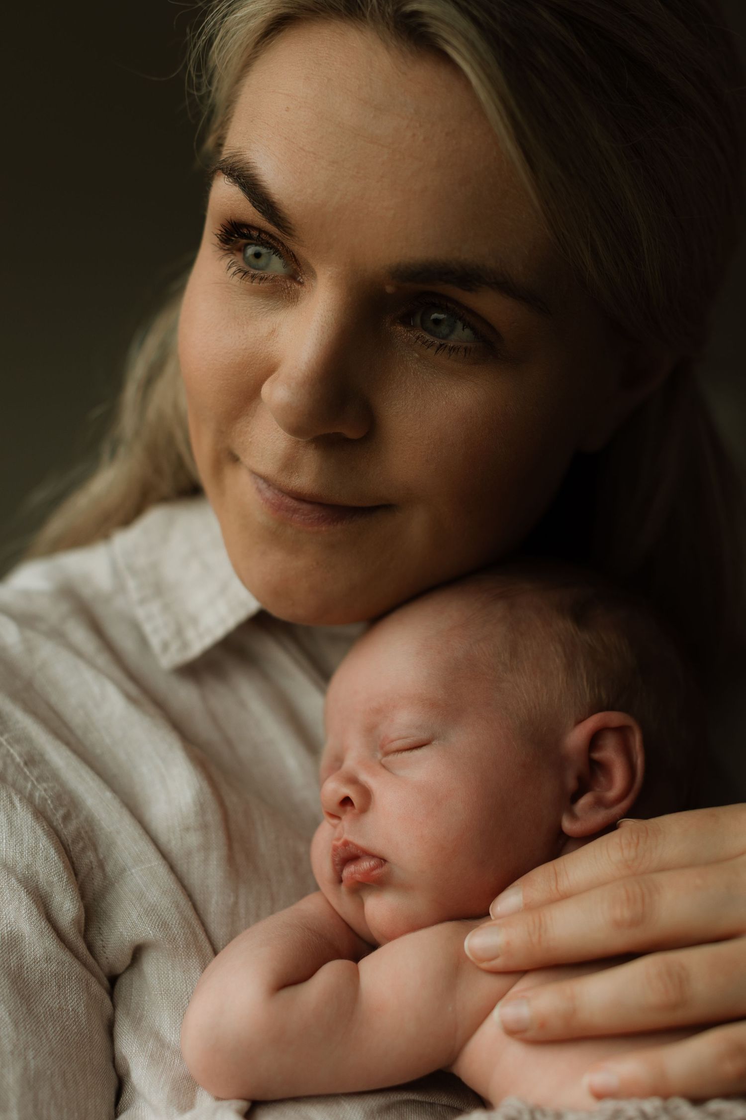Nyfødt baby som ligger fredfult og sover inntil morens bryst