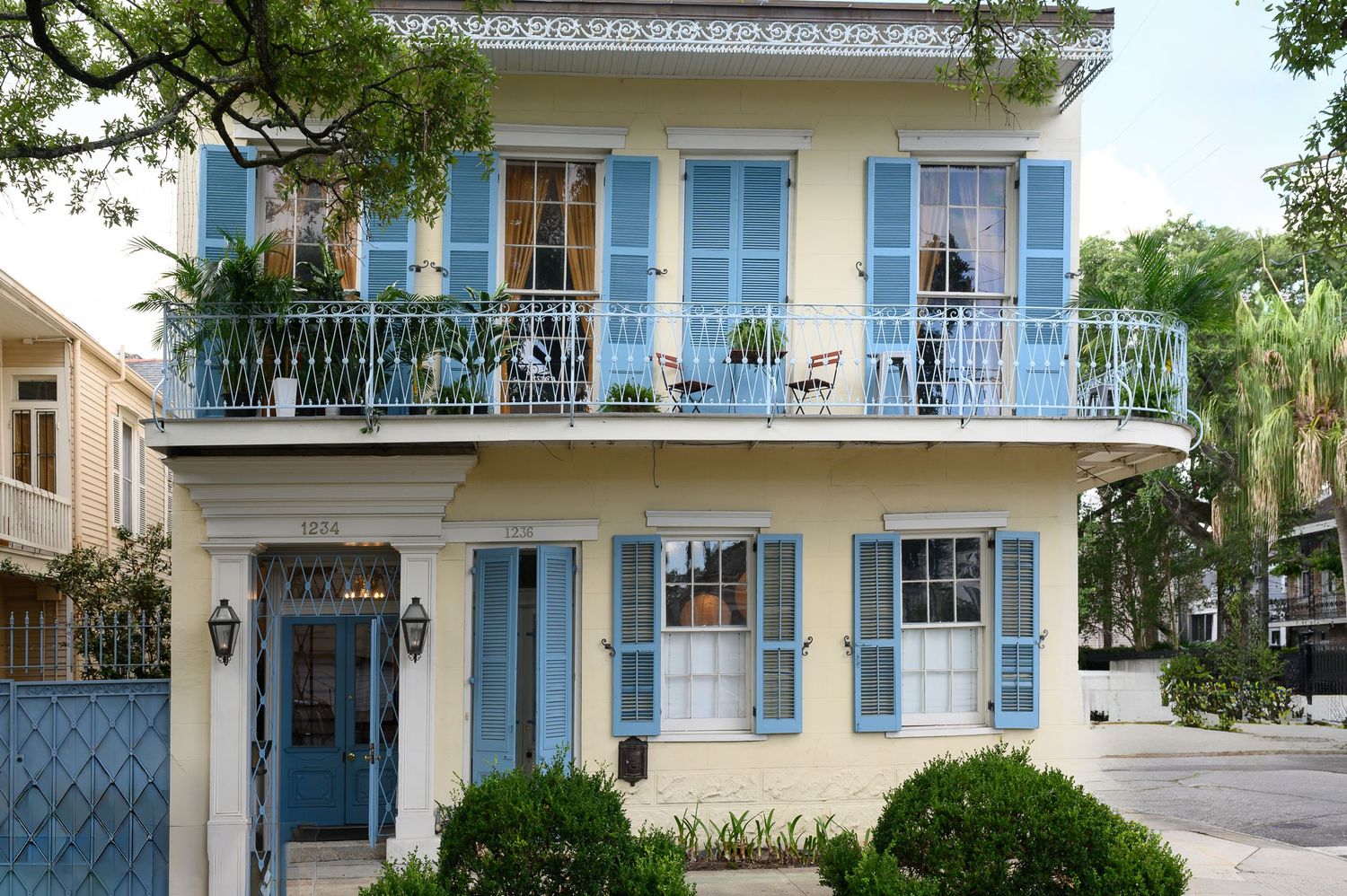 Classic New Orleans townhouse with blue shutters, wrought iron balcony and cream colored facade.