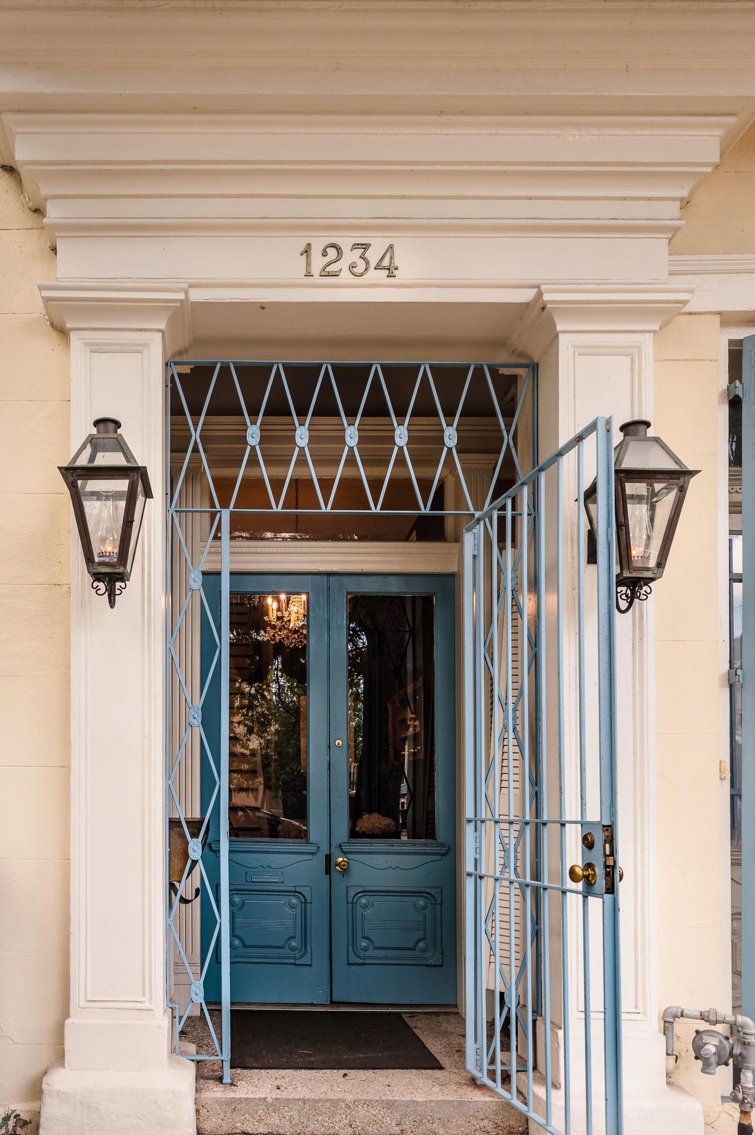 Classic white building facade with blue doors and decorative ironwork gates showcasing traditional architectural details.