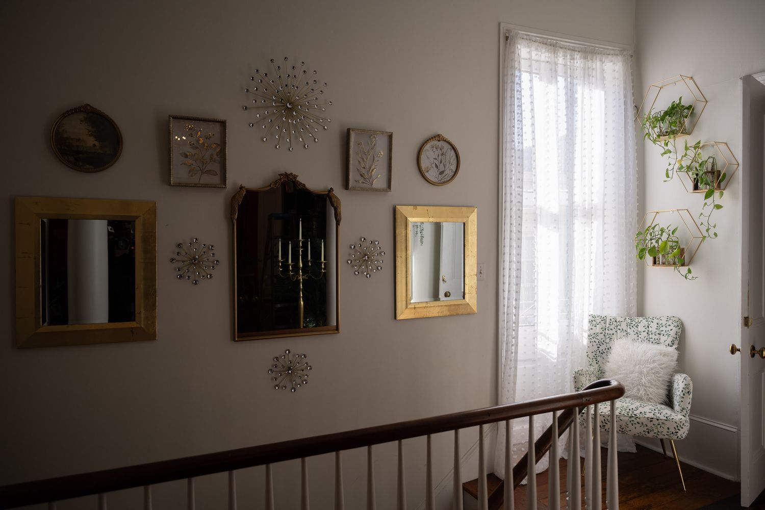 Modern staircase with dark wood railing and white walls decorated with sunburst mirrors and framed artwork.