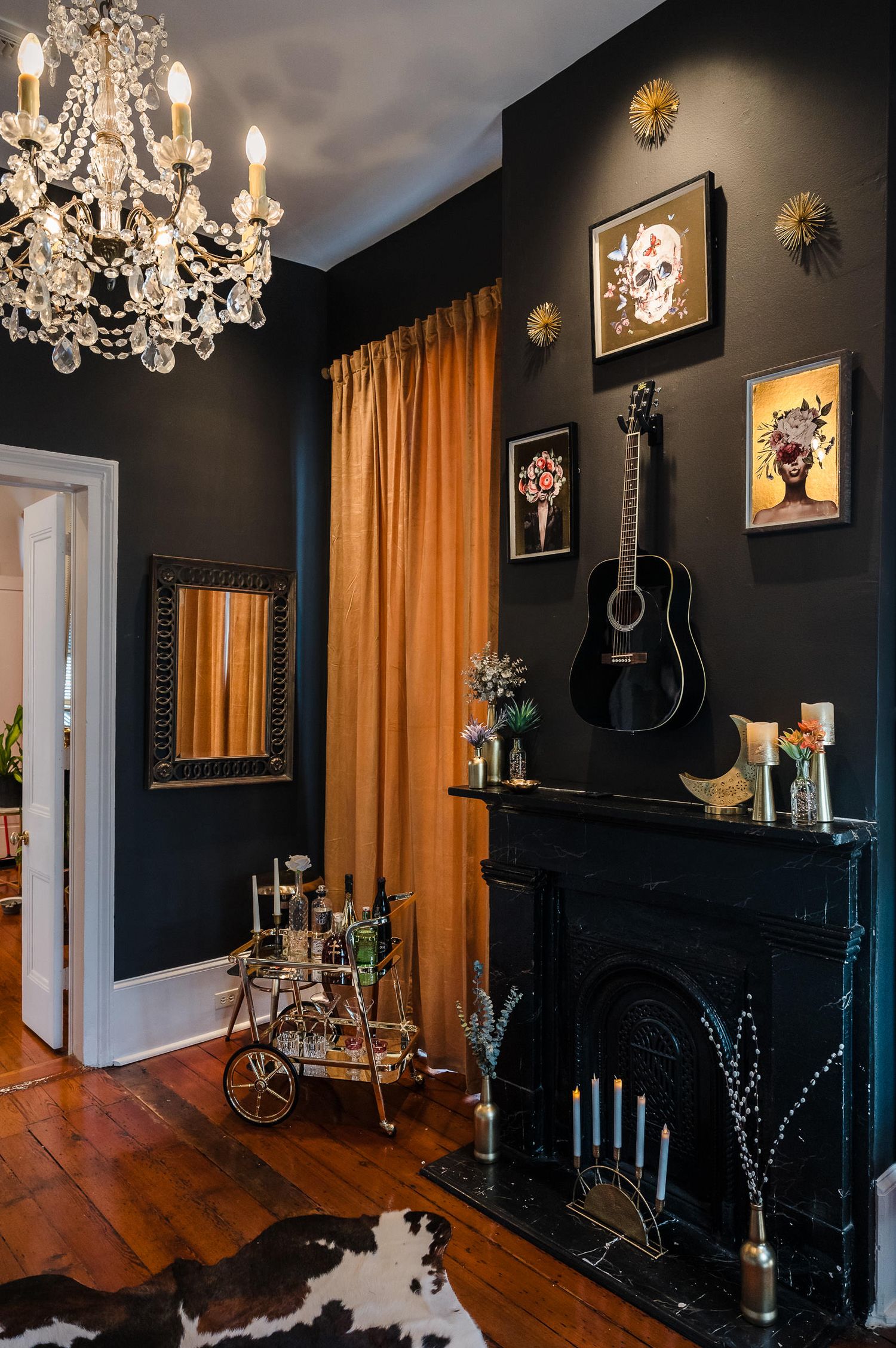 Elegant dining room with black walls, crystal chandelier, gold curtains, and hardwood floors showcases dramatic Victorian style decor.