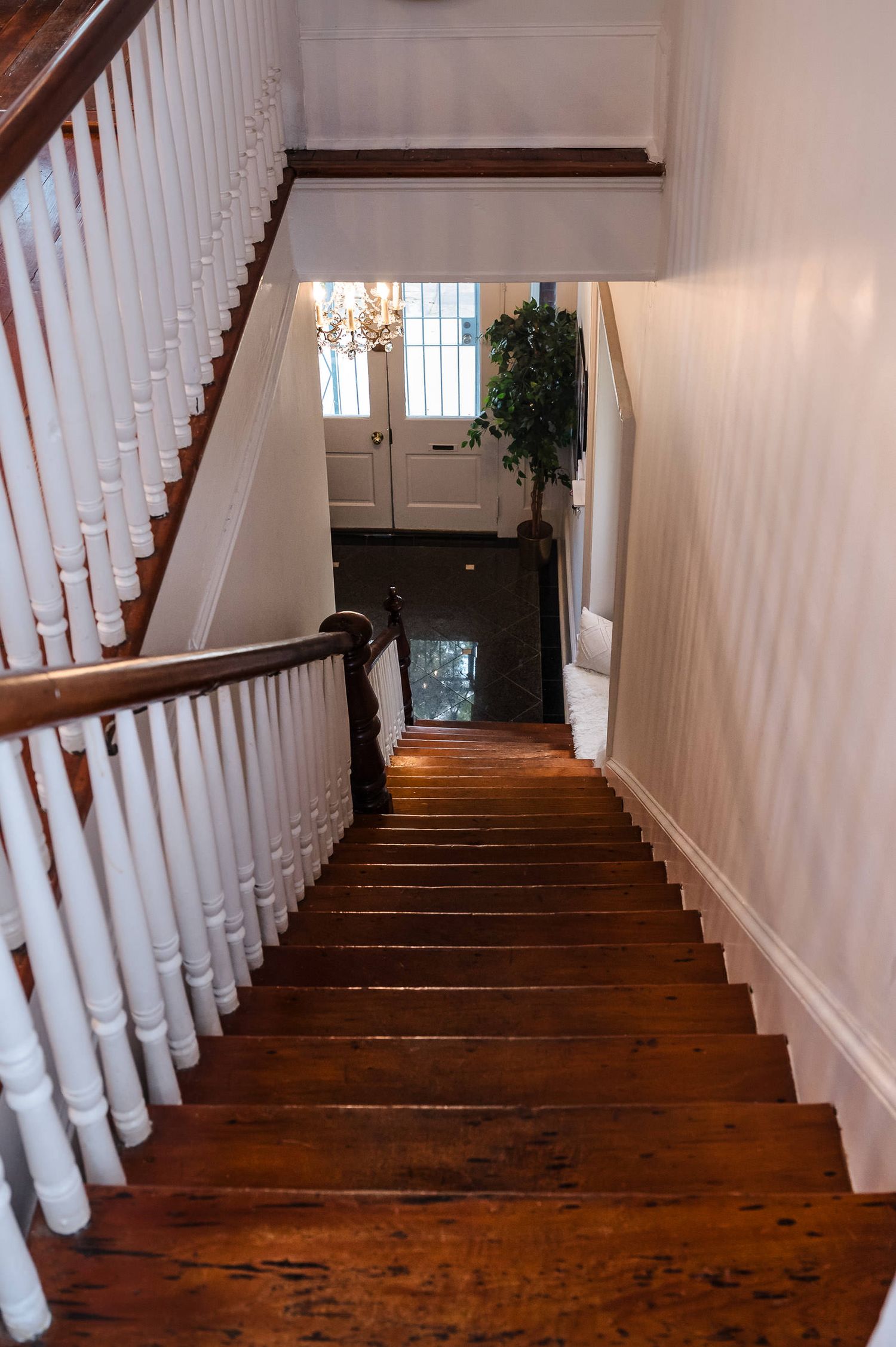 Dark hardwood staircase with white spindle railings ascending in a traditional home interior.