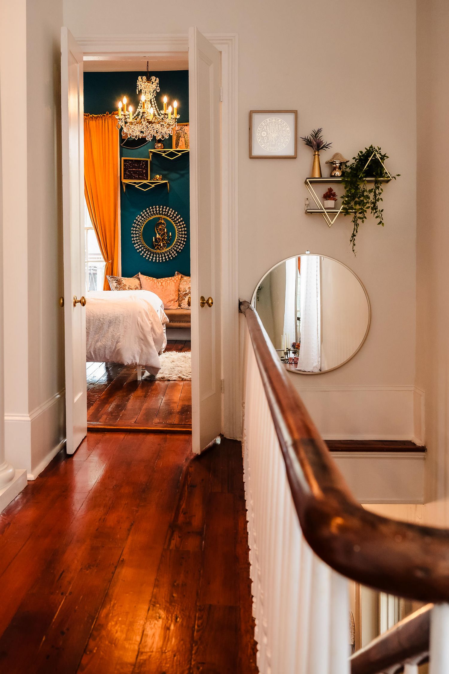 Elegant hallway with rich hardwood floors, white walls, and chandeliers showcases a series of mirrored reflections.