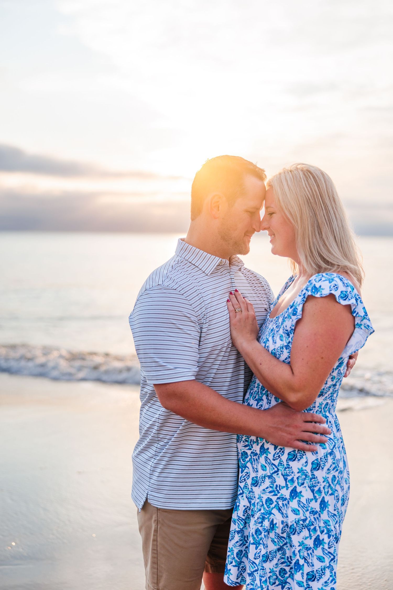 Romantic couple embracing on beach at sunset with waves in background.