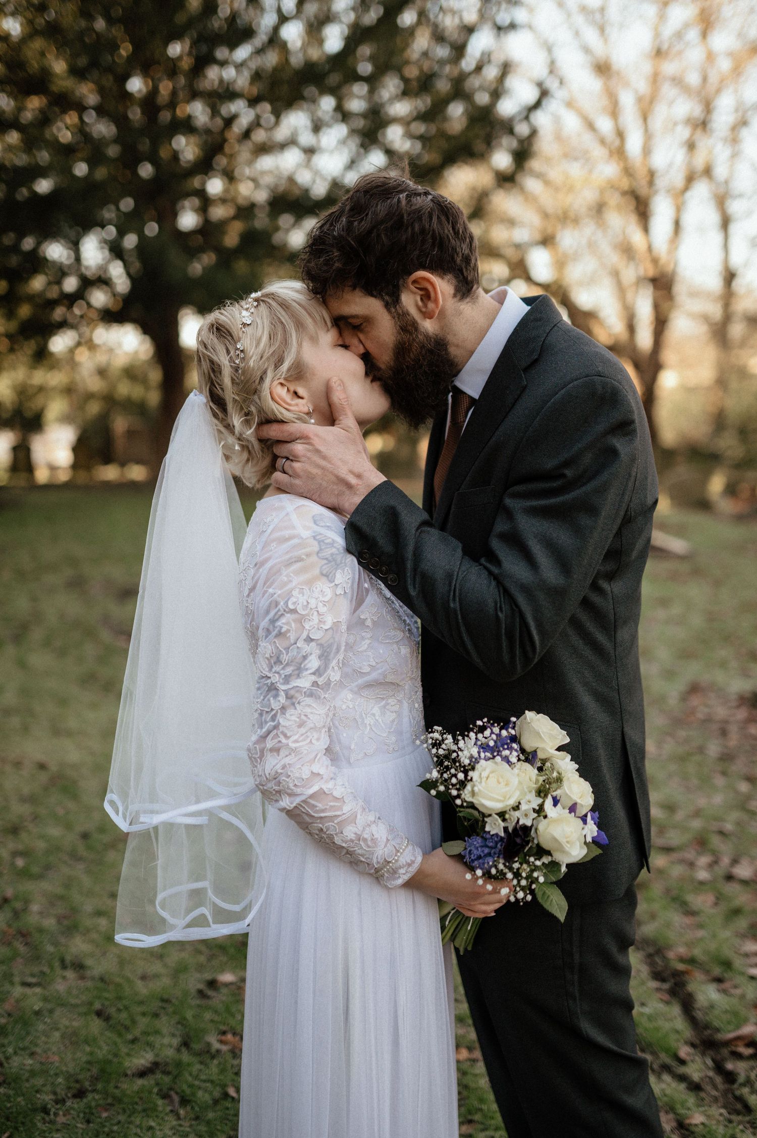Wedding couple walking through a rustic brick archway wearing cream colored outfits.