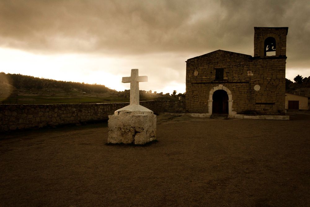 La Sierra Tarahumara, Chihuahua, México.Stone cross and old church under moody sepia sky creating atmospheric scene.