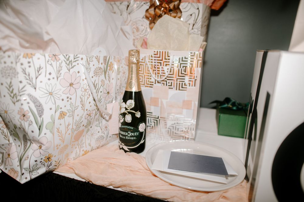 Perrier-Jouët champagne bottle displayed with wrapped gifts and a tablet on a table at an elegant event.