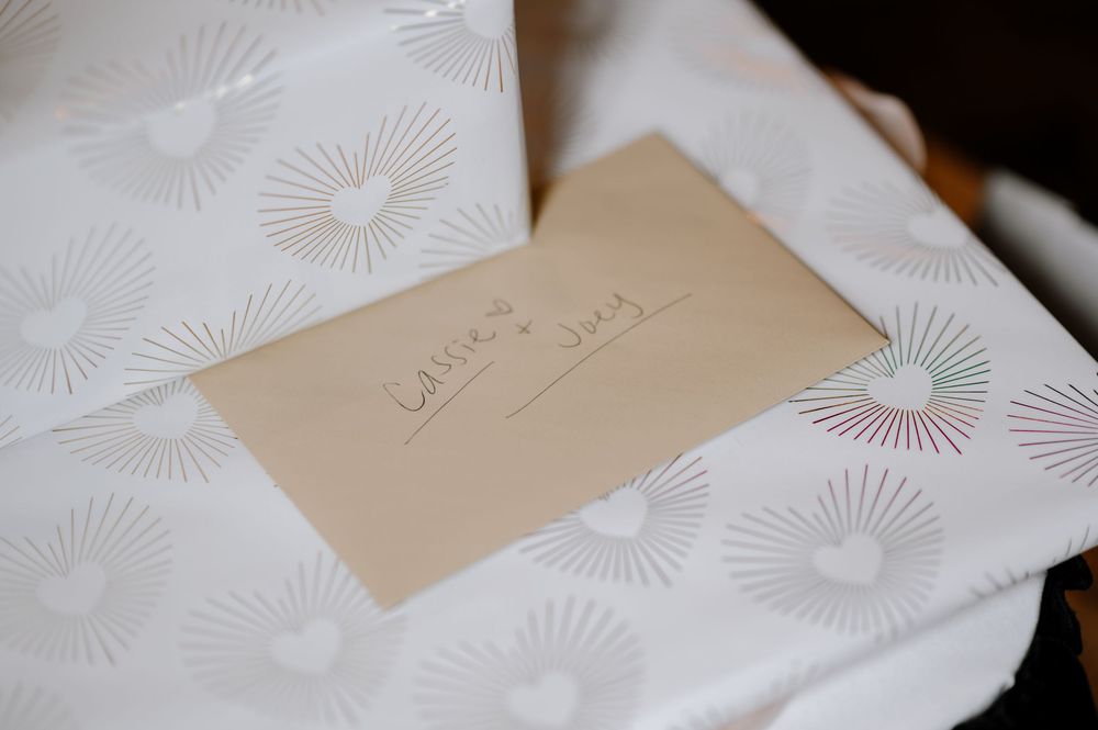 A handwritten envelope labeled Letters and Vows resting on white heart-patterned wrapping paper.