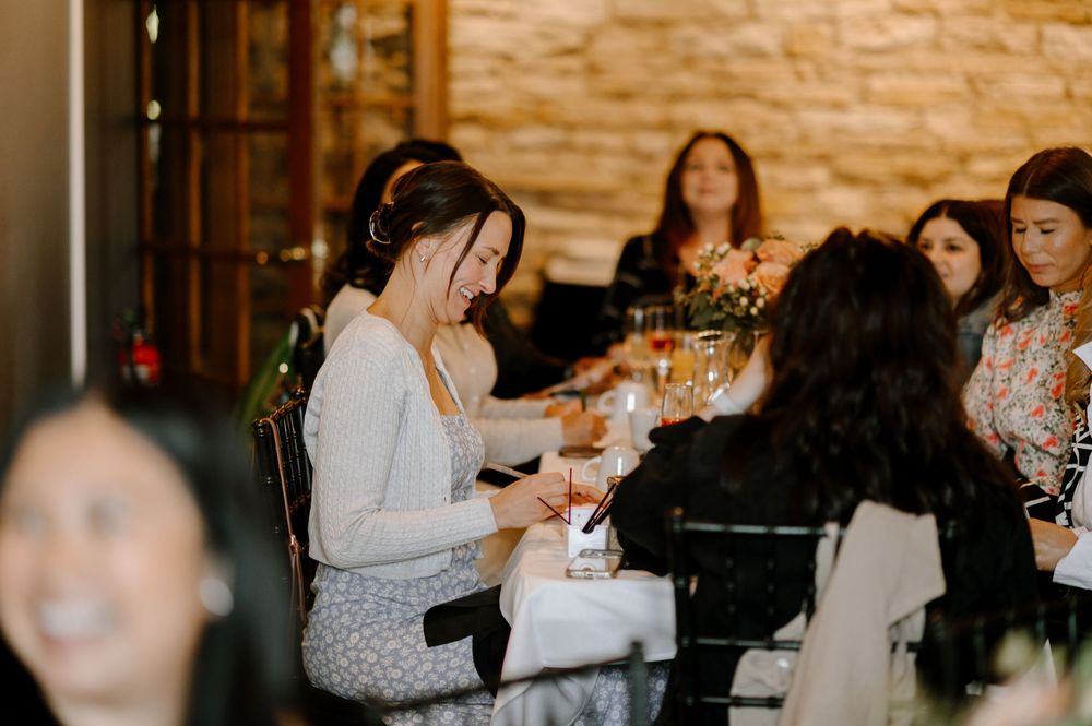Women gathered around a restaurant table, smiling and socializing during an elegant indoor dining event.