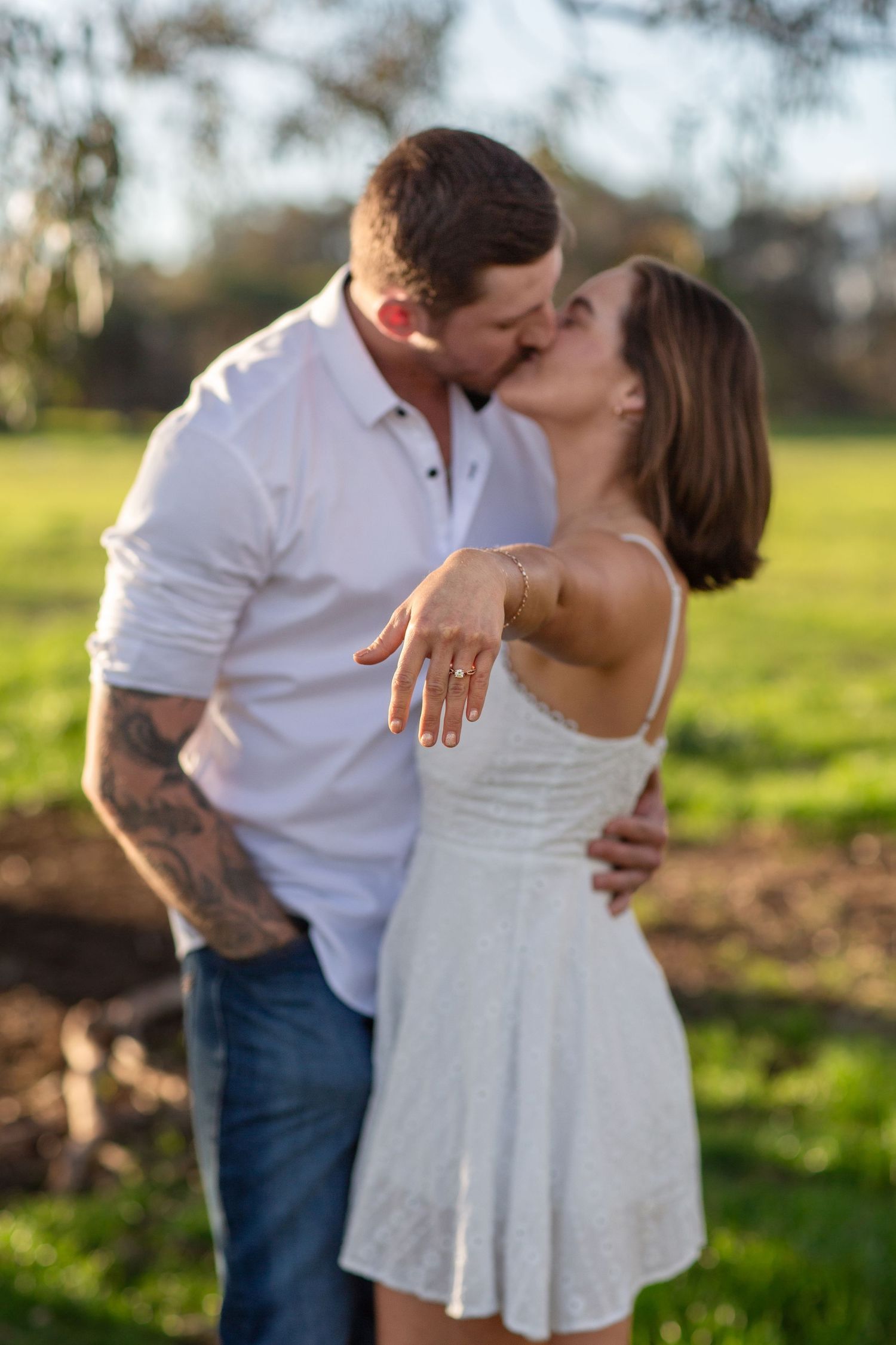 Couple holding hands with tattoos on their arm during engagement session showing engagement ring in Perth