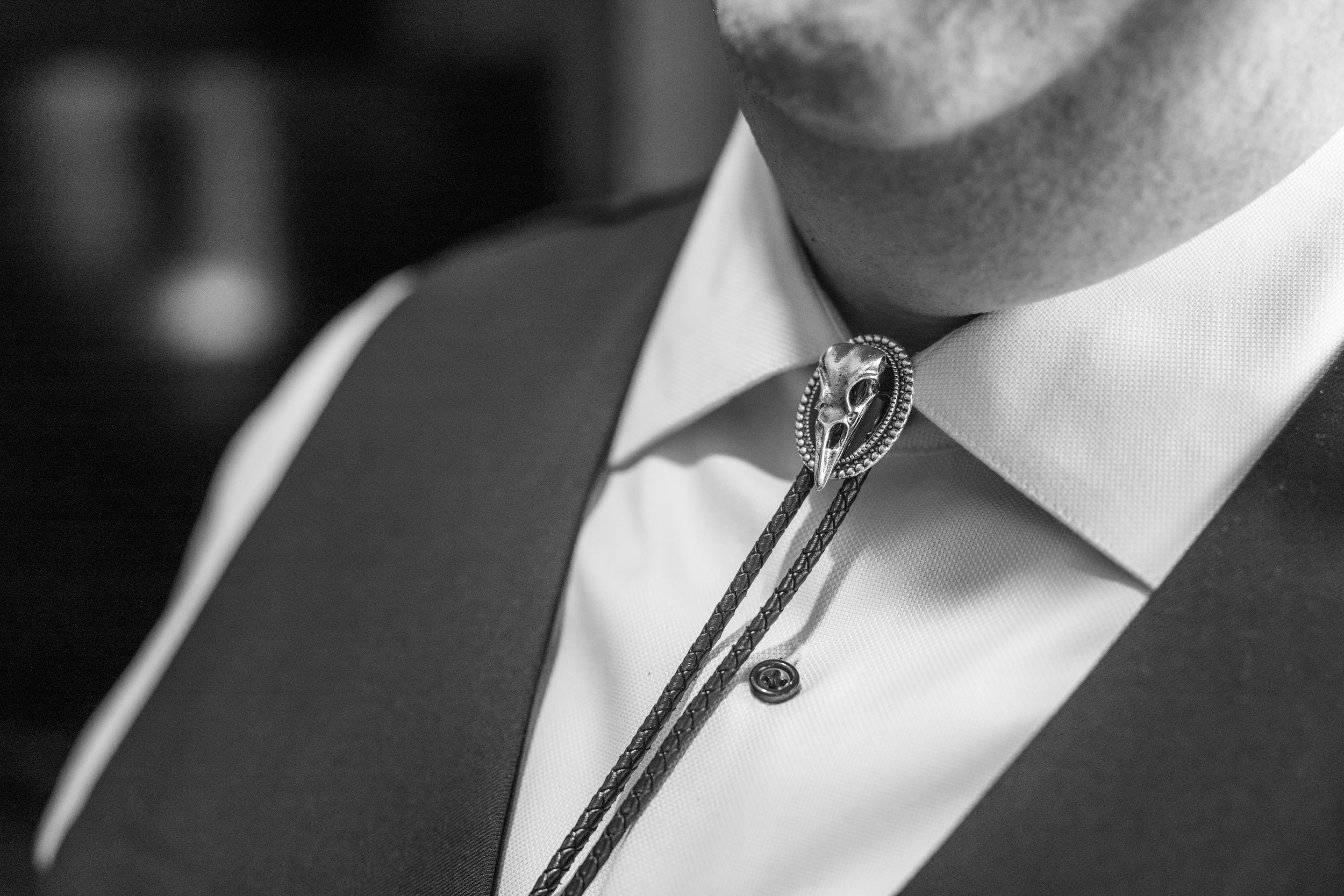 Black and white photo of a man wearing a bolo tie with decorative slide over a white dress shirt and vest.