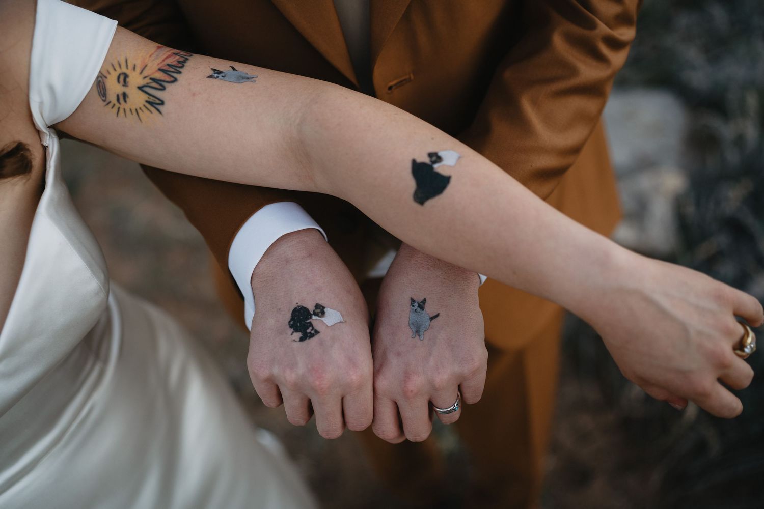 Close-up of bride and groom showing matching Peanuts character temporary tattoos on their arms and hands.
