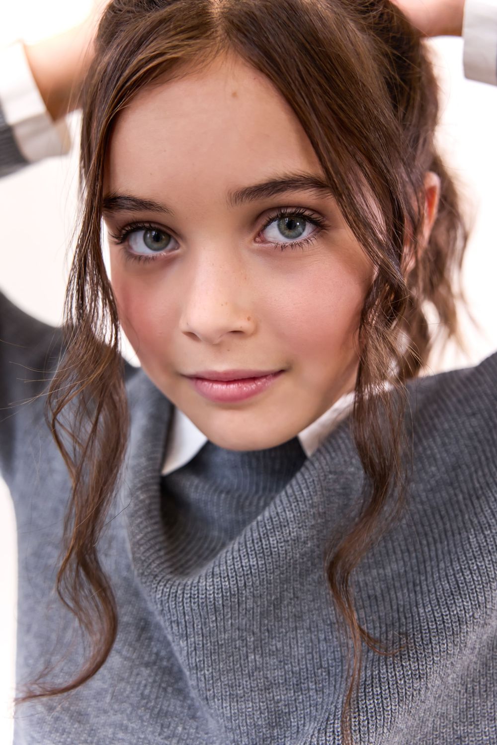 Young girl with brown hair and gray eyes wearing a gray turtleneck sweater, posing for a portrait photo.