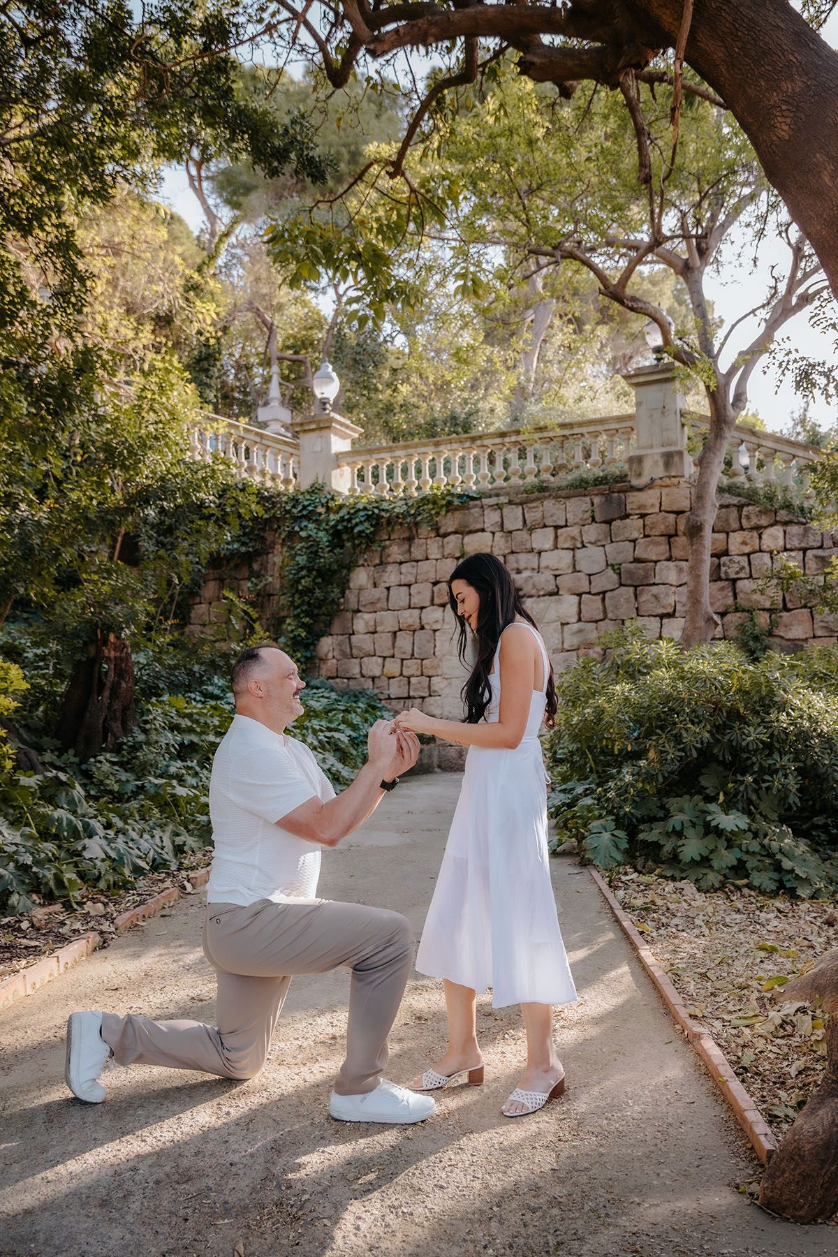 Bubbly couple laughing together during a surprise proposal photoshoot around the Montjuic fountains.