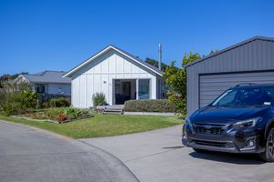 Contemporary white New Zealand home with board and batten exterior, manicured lawn, and garage.