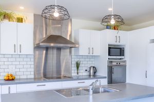 Modern white kitchen with subway tile backsplash, stainless steel appliances, and pendant lighting.