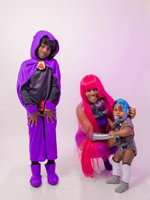 Family dressed in Teen Titans cosplay costumes, featuring Raven, Starfire, and Cyborg characters.