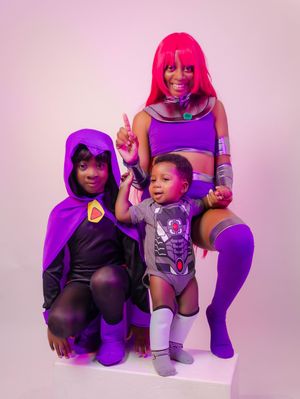 Three people in Teen Titans cosplay costumes, featuring Raven and Starfire characters, posing together in a studio.
