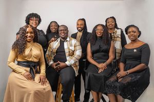 A group of eight professionally dressed individuals posing together for a formal group photo against a white background.