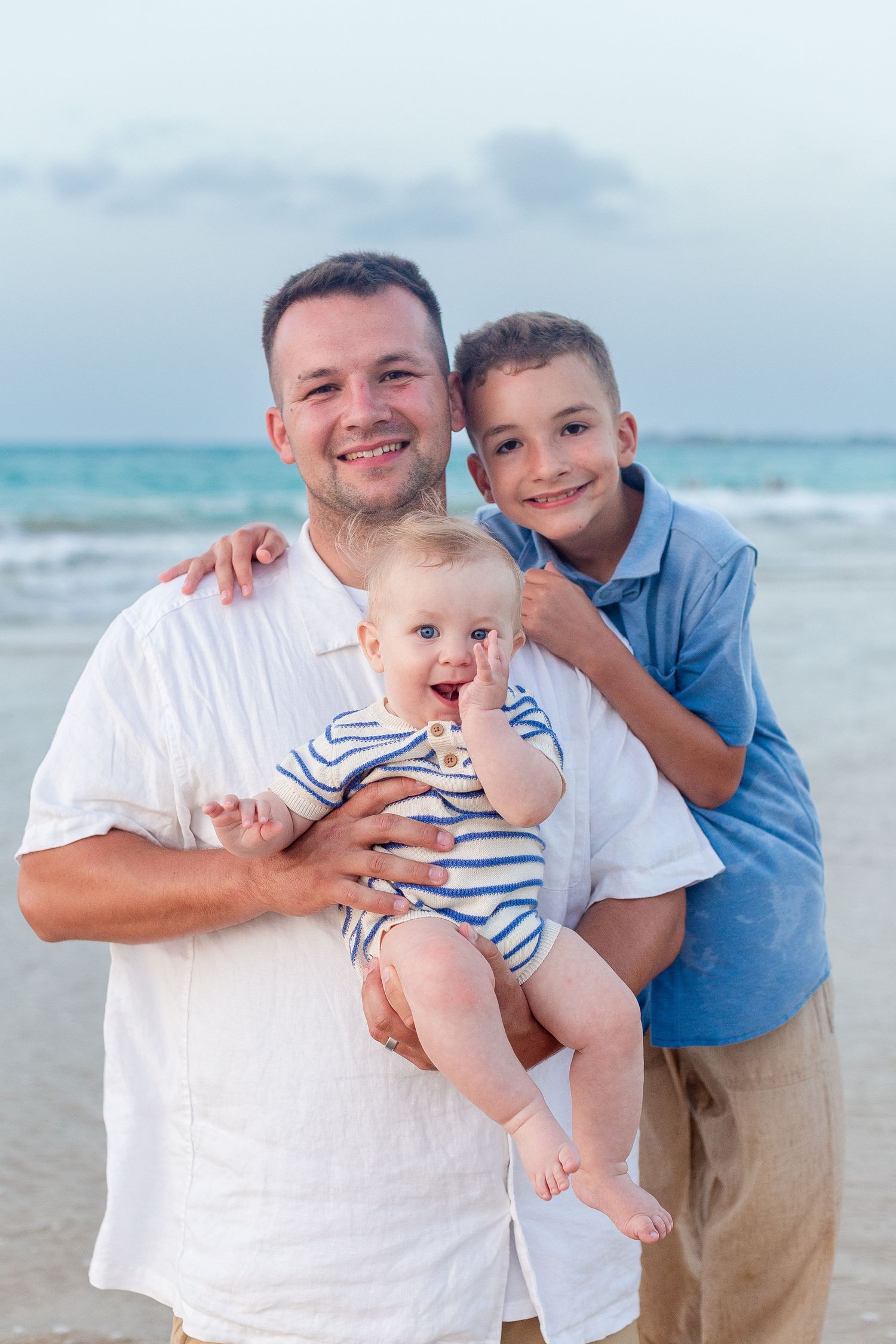 Family portrait on the beach in Isla Verde, Carolina, Puerto Rico. Father and two boys.