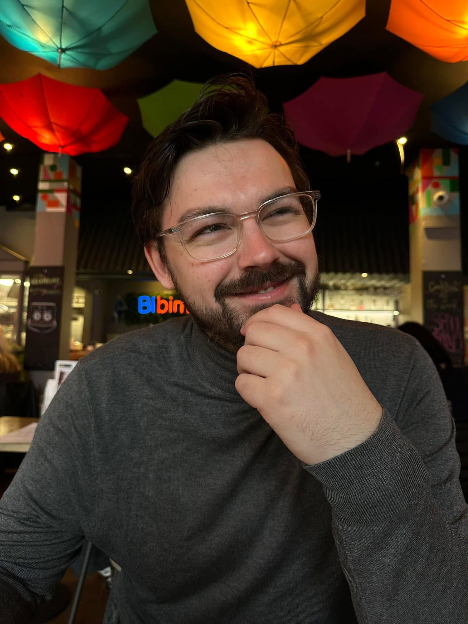 A photo of Calvin Ferries, smiling under colourful umbrellas
