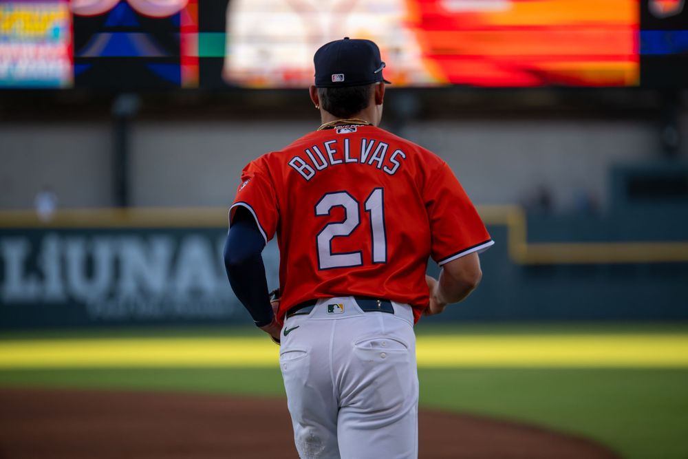 Baseball player Buelvas wearing number 21 red jersey stands on field during a game.