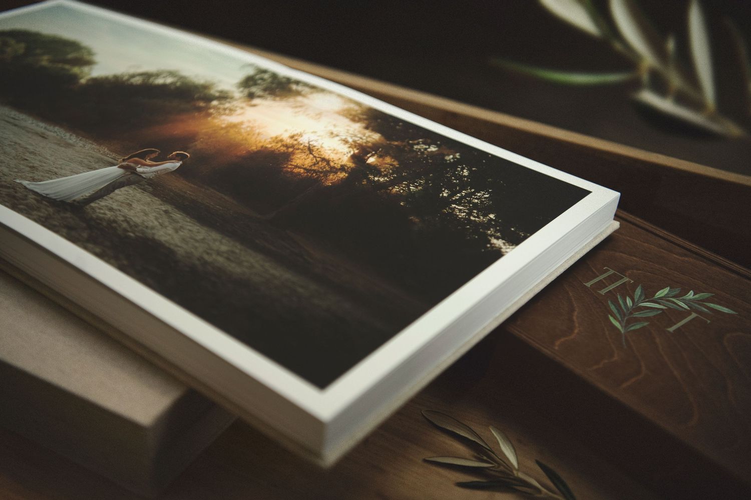 Luxury wedding album open layout displaying fine art golden hour couple prints next to a custom wooden presentation box.