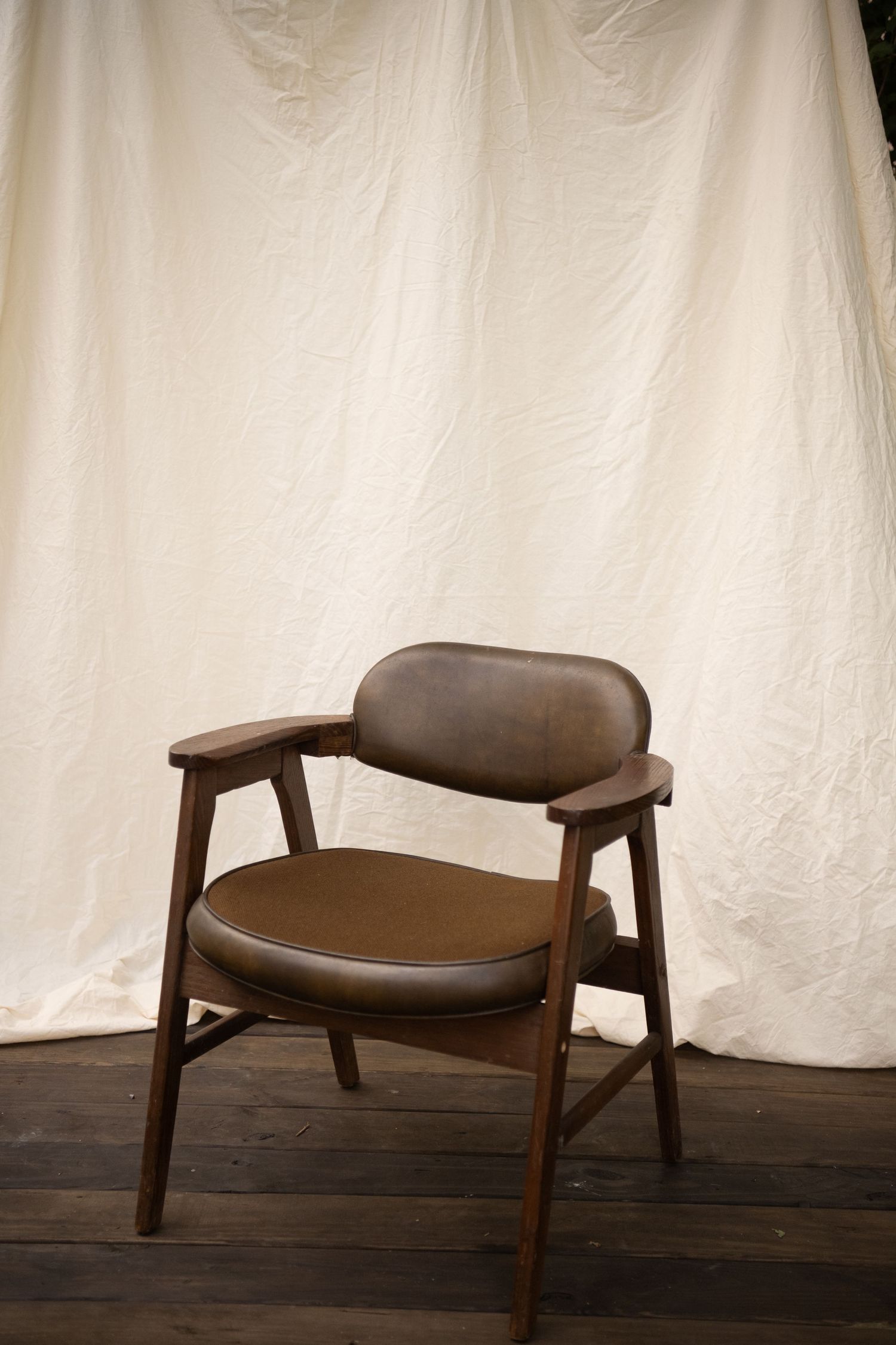 Large white fabric backdrop hung on wooden frame outdoors on a pallet stage, surrounded by green trees.