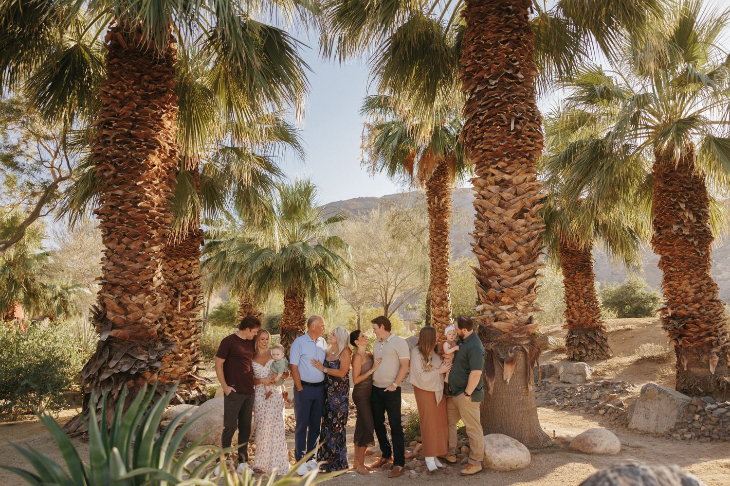 Couple standing outside a mid-century modern stone building with cacti and palm trees in Palm Springs.