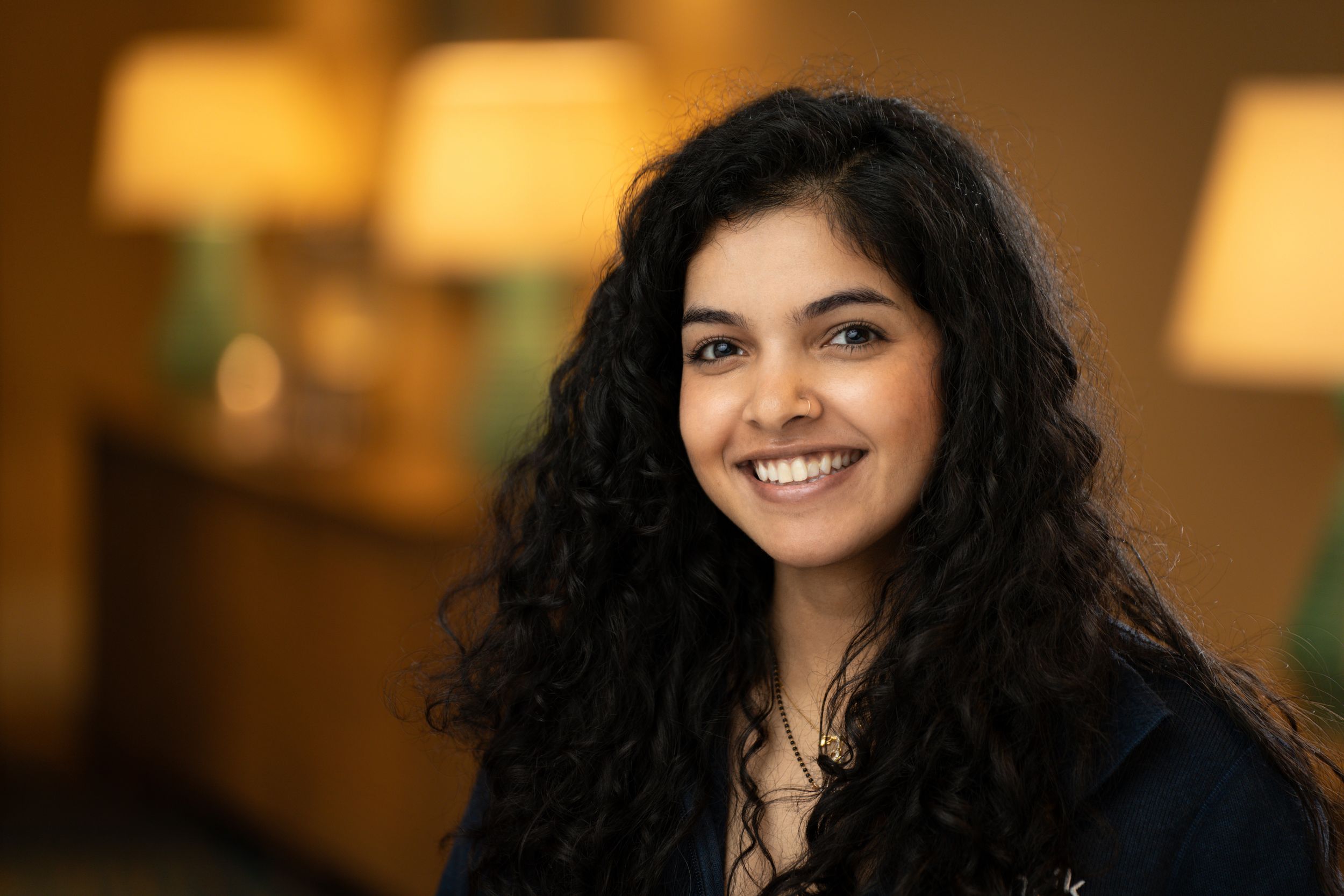A series of headshots showing a smiling woman with dark curly hair in soft warm lighting.