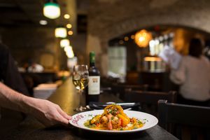 A plated gourmet pasta dish being served in a dimly lit restaurant setting.