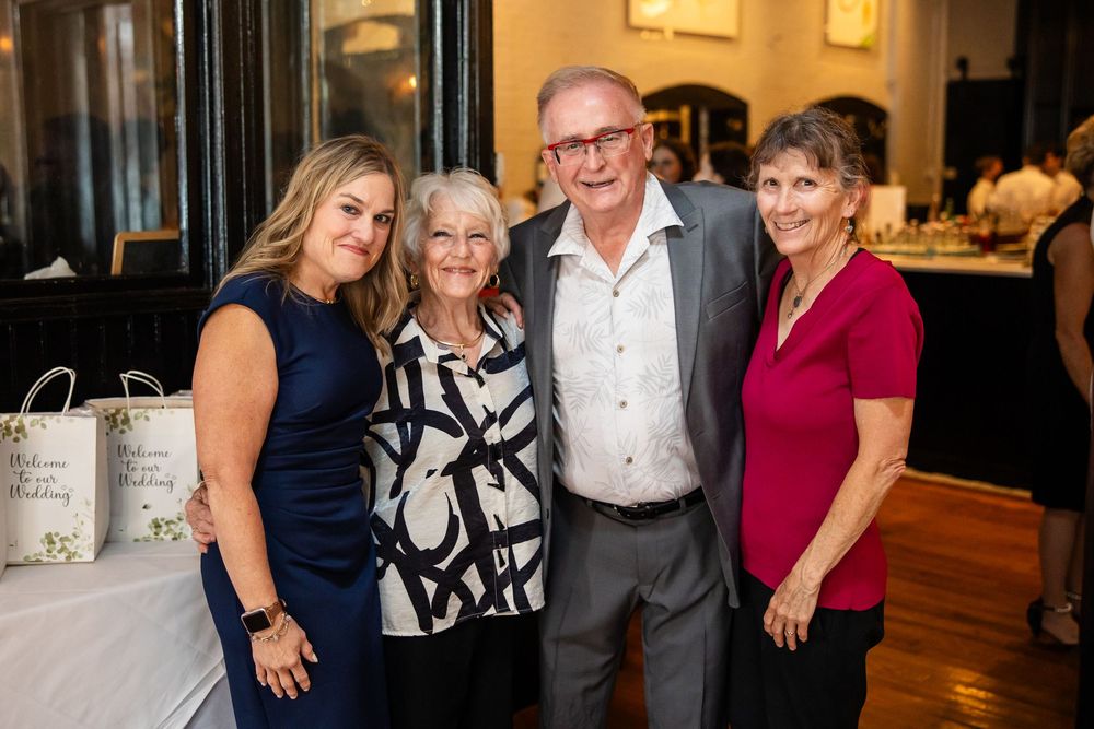 Four smiling adults posing together at an elegant indoor event, dressed in formal attire.